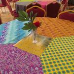 (My Handmade Tablecloths and Simple Centerpiece)
​Each table's centerpiece consisted of a glossy cardstock paper with Indian motifs/patterns and a single red carnation with palm leaf in a bud vase. I then sprinkled multi colored sequins around this display for added sparkle. ~