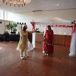 (Fabric Mandap)
This mandap boasted red, a traditional wedding color. Sheer and tulle fabrics canopied overhead for the ceremony. Floral designs consisting of red roses and peacock feathers ancored the top front corners.What a beautiful couple as they dance in their Indian attire! ~