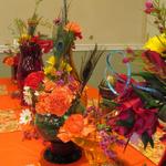 (Exotic Floral Table Centerpieces)
I imagined the tablesettings being colorful and exotic. Centered on the tables were colored glass vases and containers (rentable) with all the same flowers and peacock feathers used on the mandap. An Indian motif fabric was photocopied and used as a placemat to add