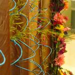 (Embellishments on Mandap)
The fabric for the backdrop was an antique gold broque satin. The blue glitter sticks   (I call  them squiggles) were hung to compliment the bride's blue sari and to  add interest  and texture - especially for photos. Within the "squiggles" hung flower buds and greens. ~